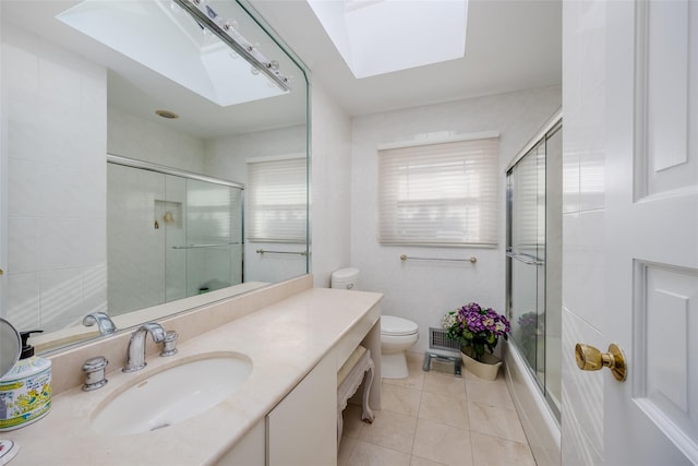 full bath featuring a skylight, bath / shower combo with glass door, toilet, vanity, and tile patterned flooring