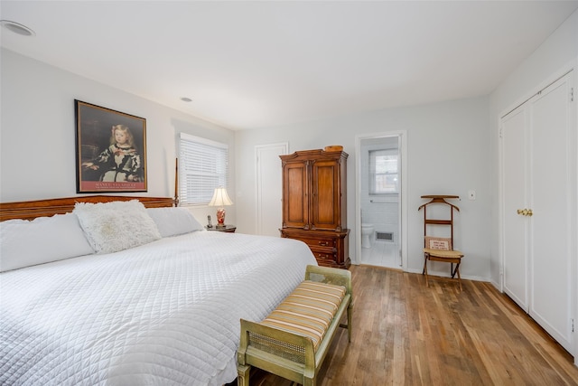 bedroom featuring visible vents, wood finished floors, and ensuite bathroom