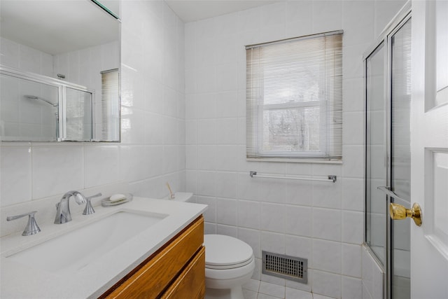 full bathroom featuring tile walls, bath / shower combo with glass door, visible vents, toilet, and vanity