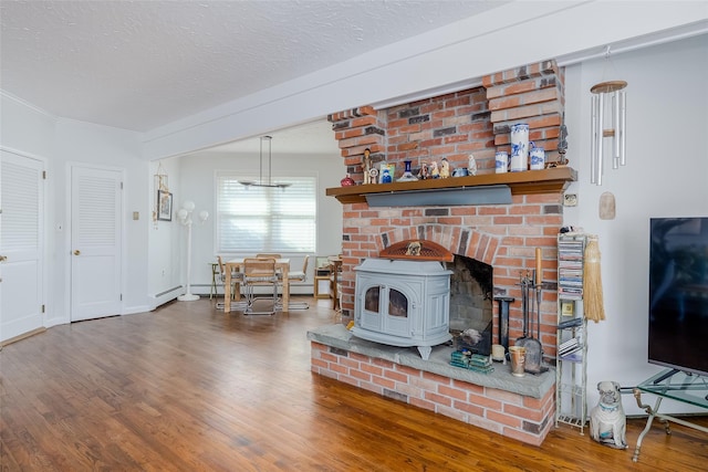 living area with baseboards, ornamental molding, wood finished floors, a wood stove, and a textured ceiling