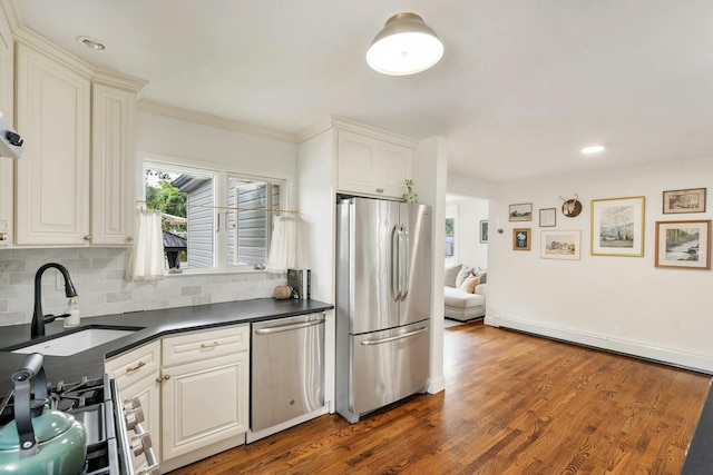 kitchen featuring dark wood-type flooring, sink, backsplash, appliances with stainless steel finishes, and white cabinets