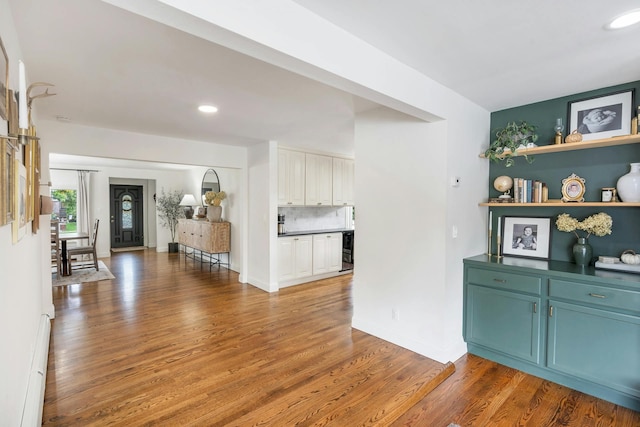 interior space with wine cooler, wood-type flooring, and a baseboard heating unit