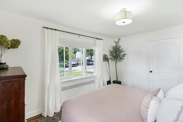 bedroom with dark hardwood / wood-style flooring and radiator