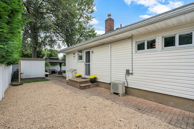 rear view of house featuring a gazebo, a shed, a patio area, and ac unit