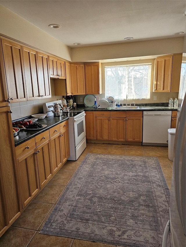 kitchen with sink, white appliances, and dark tile patterned floors