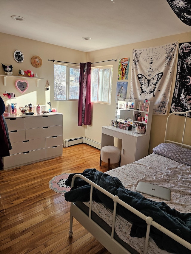 bedroom with light hardwood / wood-style floors and baseboard heating