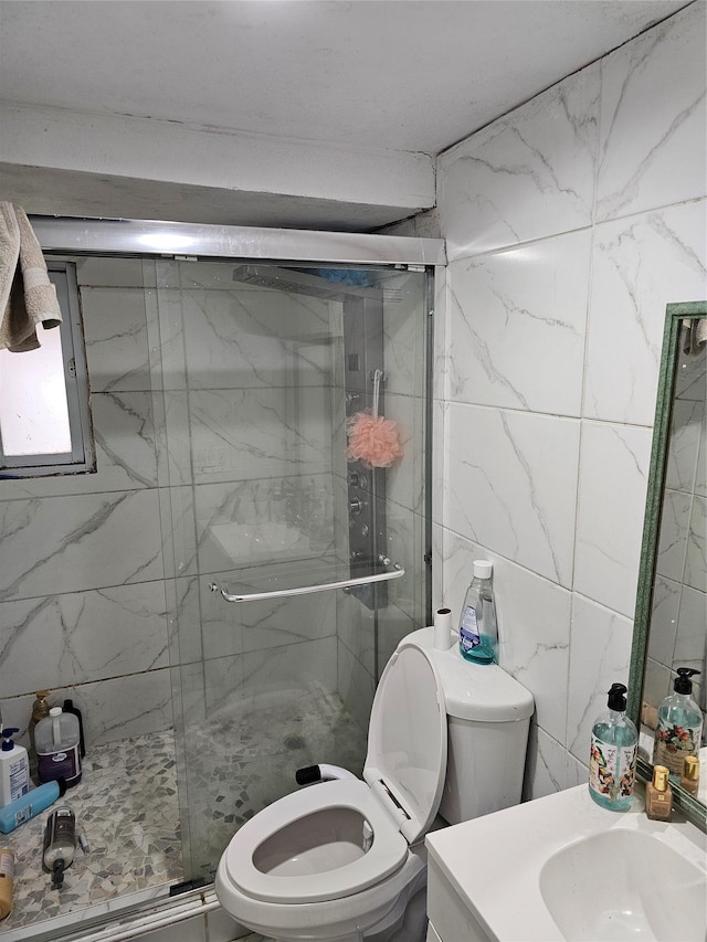 bathroom with vanity, a shower with shower door, tile walls, and toilet