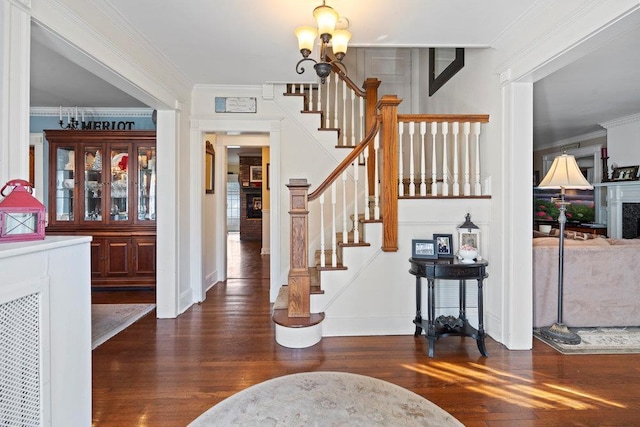 entrance foyer with ornamental molding, dark hardwood / wood-style floors, and a chandelier