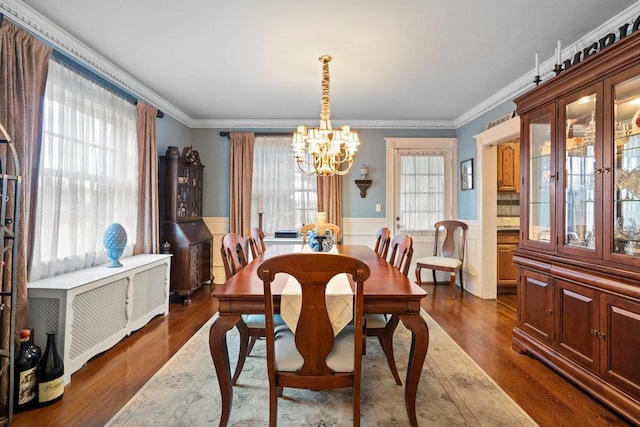 dining room with an inviting chandelier, ornamental molding, and dark hardwood / wood-style flooring