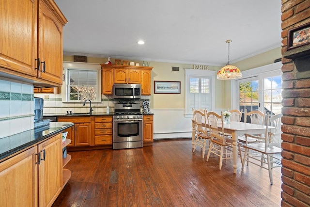 kitchen with pendant lighting, sink, baseboard heating, appliances with stainless steel finishes, and plenty of natural light