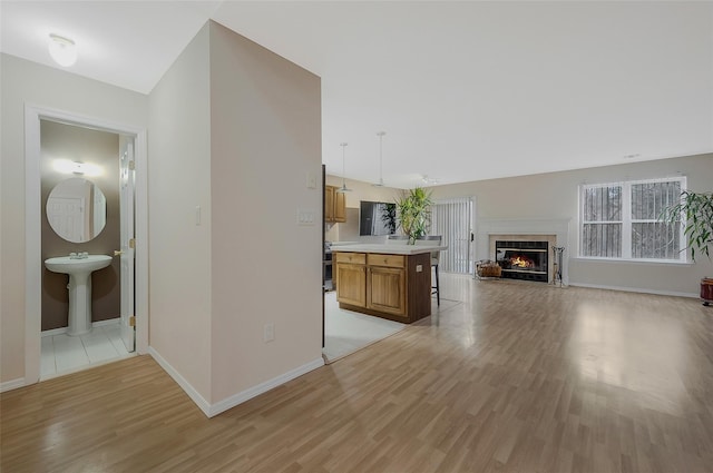 unfurnished living room with a tile fireplace, sink, and light hardwood / wood-style floors