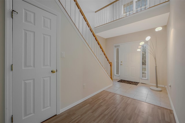 foyer entrance featuring a towering ceiling and light hardwood / wood-style floors