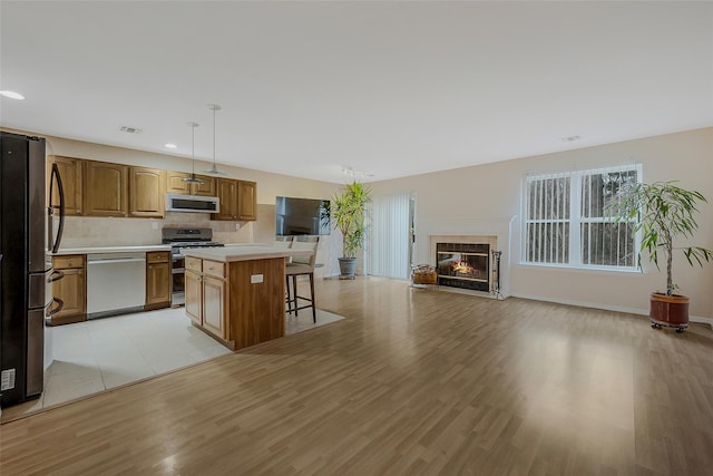 kitchen featuring a breakfast bar, hanging light fixtures, light hardwood / wood-style flooring, a kitchen island, and stainless steel appliances