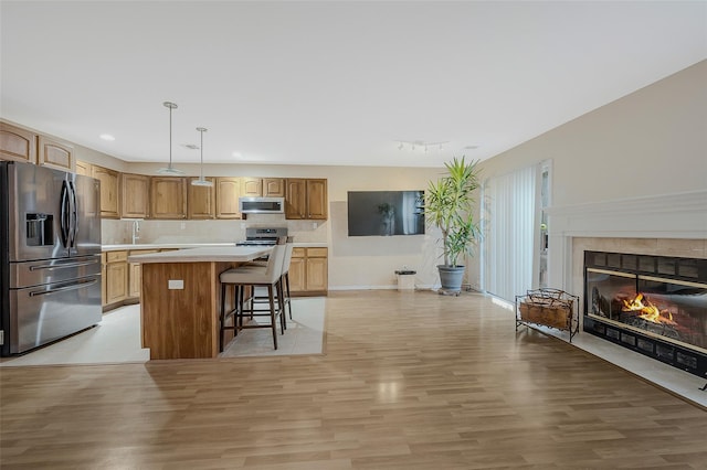 kitchen with pendant lighting, light hardwood / wood-style flooring, a breakfast bar, stainless steel appliances, and a center island