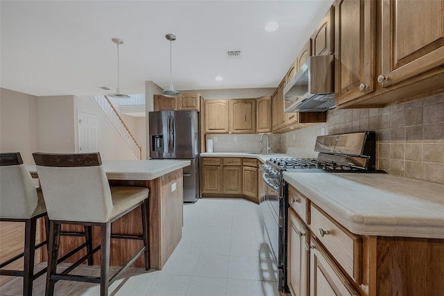 kitchen featuring sink, stainless steel appliances, a center island, a kitchen breakfast bar, and decorative light fixtures