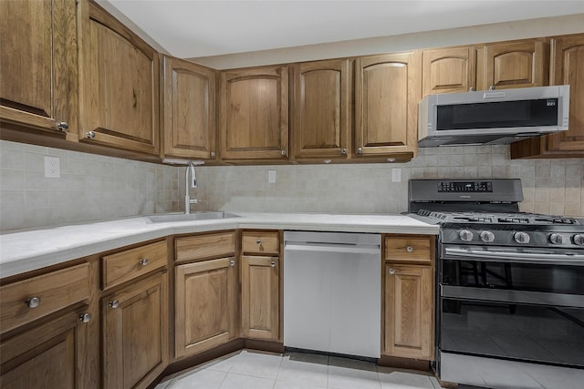 kitchen with tasteful backsplash, light tile patterned flooring, appliances with stainless steel finishes, and sink