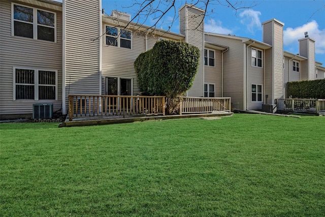 back of house with a wooden deck, a lawn, and central air condition unit