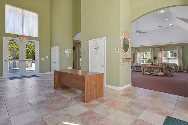 interior space with light colored carpet, french doors, ceiling fan, and a high ceiling