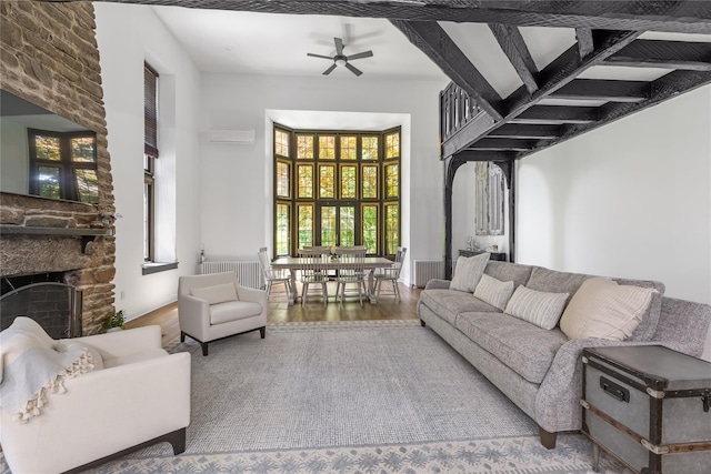 living room featuring hardwood / wood-style flooring, ceiling fan, a towering ceiling, a fireplace, and an AC wall unit