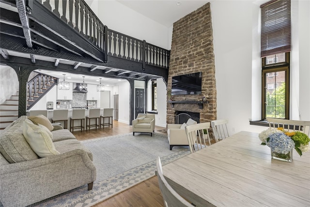 living room with a towering ceiling, a stone fireplace, and light hardwood / wood-style flooring