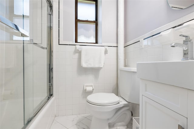 full bathroom with vanity, combined bath / shower with glass door, tile walls, and toilet