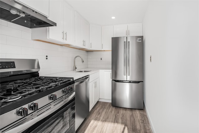 kitchen featuring hardwood / wood-style flooring, range hood, sink, white cabinets, and stainless steel appliances