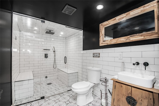 bathroom with toilet, an enclosed shower, tile walls, tile patterned floors, and vanity