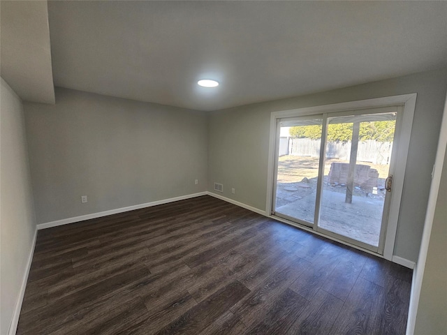 spare room featuring visible vents, baseboards, and dark wood finished floors