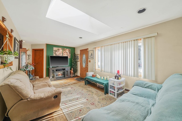 living room featuring hardwood / wood-style flooring, a baseboard heating unit, and a skylight