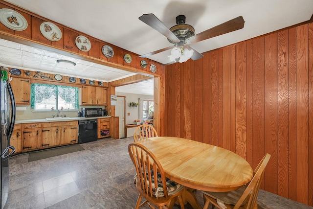 dining area with sink, ceiling fan, and wood walls