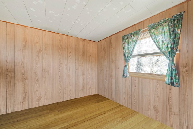 empty room featuring hardwood / wood-style flooring and wooden walls