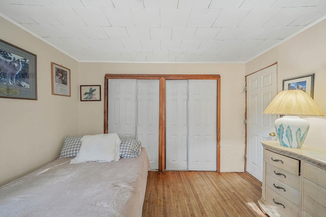 bedroom featuring ornamental molding, light hardwood / wood-style floors, and two closets