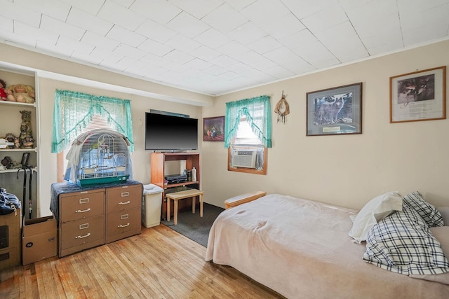 bedroom with crown molding, cooling unit, and light hardwood / wood-style floors