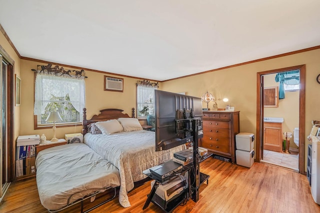 bedroom featuring ensuite bath, ornamental molding, a wall mounted AC, and light hardwood / wood-style flooring