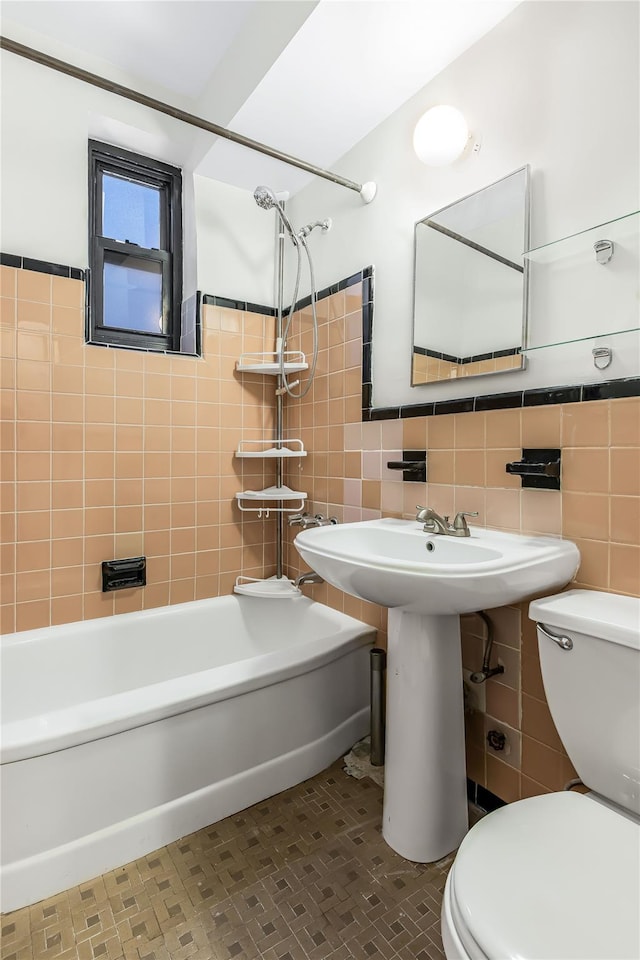 bathroom with tiled shower / bath, toilet, tile patterned flooring, and tile walls