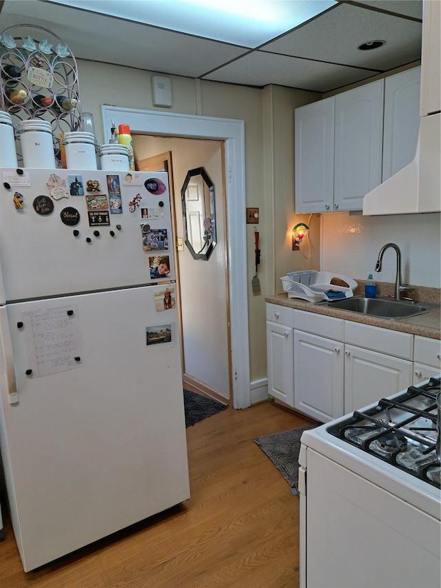 kitchen featuring white cabinets, white appliances, light hardwood / wood-style flooring, and sink