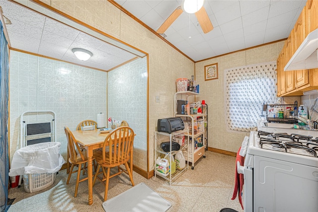 dining area with ceiling fan, crown molding, and tile walls