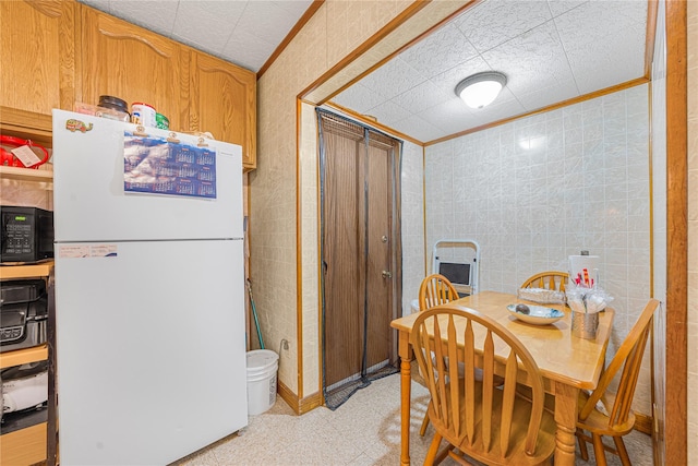 dining area featuring crown molding and tile walls