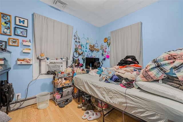 bedroom featuring baseboard heating, hardwood / wood-style floors, and cooling unit