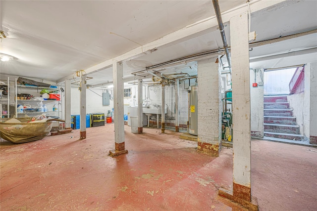 basement featuring electric panel, gas water heater, washer / clothes dryer, and sink