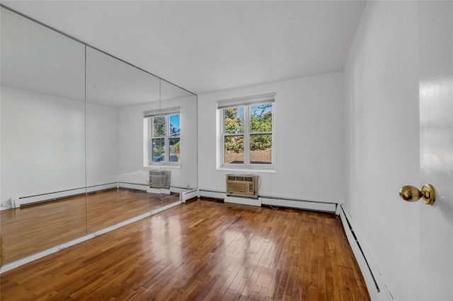 unfurnished room featuring hardwood / wood-style floors, a wall mounted AC, and a baseboard heating unit