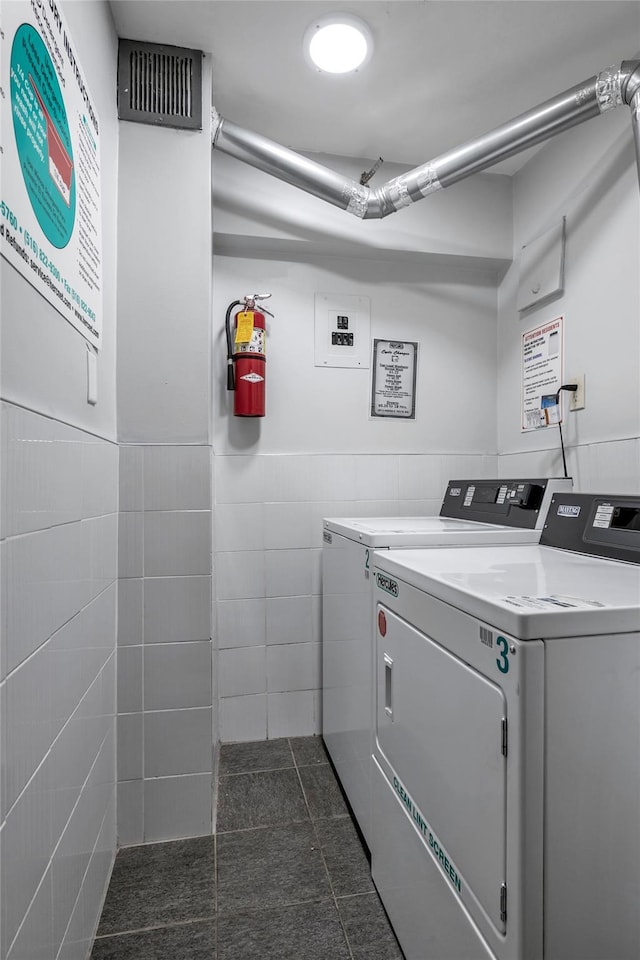 clothes washing area with tile walls and washer and clothes dryer