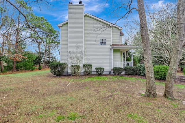 view of side of home with covered porch and a yard