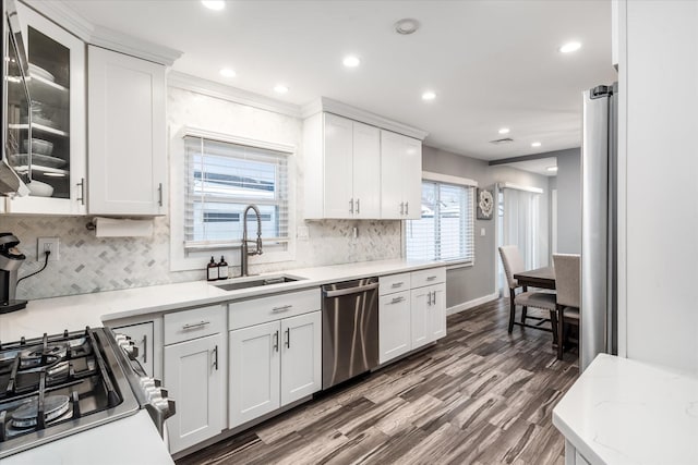 kitchen with decorative backsplash, white cabinets, sink, dark wood-type flooring, and stainless steel appliances