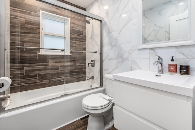 full bathroom with tile walls, tasteful backsplash, hardwood / wood-style floors, toilet, and shower / bath combination with glass door