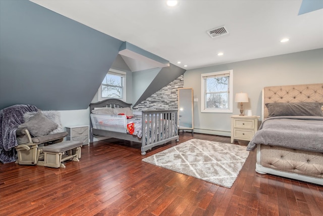 bedroom featuring a baseboard heating unit, dark hardwood / wood-style floors, and multiple windows