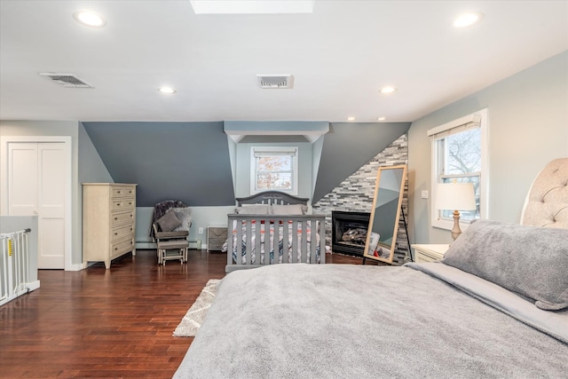 bedroom featuring a large fireplace and dark hardwood / wood-style floors