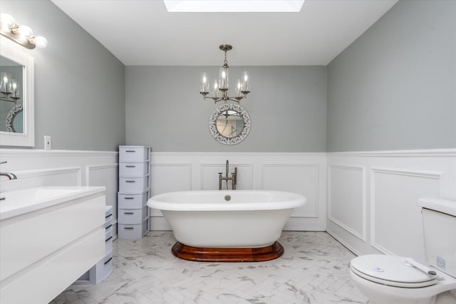 bathroom featuring a tub to relax in, toilet, a skylight, and a notable chandelier