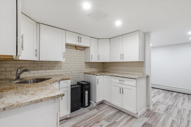 kitchen featuring sink, light wood-type flooring, white cabinetry, light stone counters, and decorative backsplash