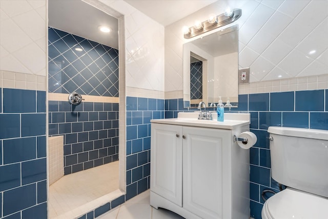 bathroom featuring toilet, a shower, tile walls, tile patterned floors, and vanity